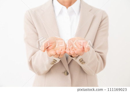 A middle-aged woman wearing a beige suit with both hands in front of her 111169023