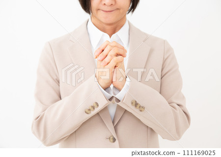 身穿米色西裝的中年婦女雙手合十許願 111169025
