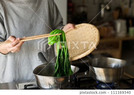 Draining the boiled spinach in a colander Draining the boiled spinach in a colander 111169340