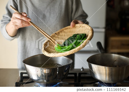 Draining the boiled spinach in a colander Draining the boiled spinach in a colander 111169342
