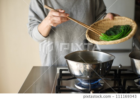 Draining the boiled spinach in a colander Draining the boiled spinach in a colander 111169343