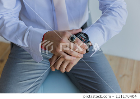 a man in a shirt puts a watch on his hand a man in a shirt puts a watch on his hand 111170404