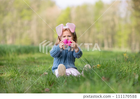 Girl with bunny ears collects the eggs for Easter Girl with bunny ears collects the eggs for Easter 111170588