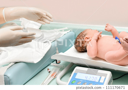 A nurse weighs on the scales of a newborn baby 111170671