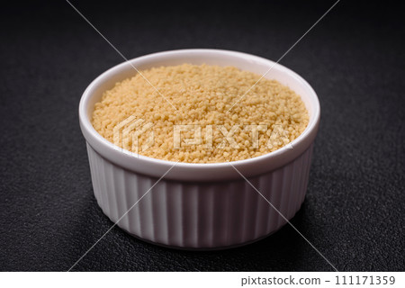 Wheat porridge couscous grains on a dark concrete background 111171359