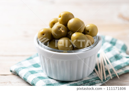 Green olives in a bowl on wooden table Green olives in a bowl on wooden table 111171806