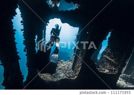 Female freediver swims underwater among the ruins of a ship. Freediving on wreck ship in ocean 111171955