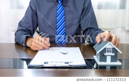 Real estate agents hand holding pen, home model, explains the business contract for signing a business contract, renting, buying, mortgage, loan or home insurance Real estate agents hand holding pen, home model, explains the business contract for signing a business contract, renting, buying, mortgage, loan or home insurance 111172313