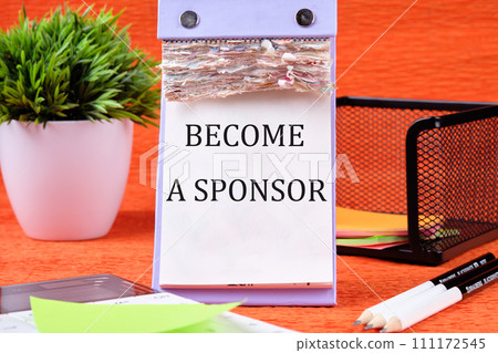 BECOME A SPONSOR text written on the page of the desktop calendar on an orange background 111172545