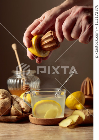 Ginger tea with lemon and honey on a brown ceramic table. 111172876