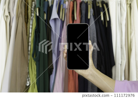手將智慧型手機放在衣架上的衣服上 111172976