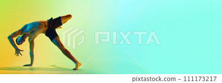 Dynamic pose. Muscular, athletic young man training shirtless, practicing against gradient blue yellow background in neon light Dynamic pose. Muscular, athletic young man training shirtless, practicing against gradient blue yellow background in neon light 111173217