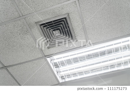 Ceiling mounted cassette type air conditioner and modern lamp light on white ceiling. Duct air conditioner for home, hall or office. Ceiling mounted cassette type air conditioner and modern lamp light on white ceiling. Duct air conditioner for home, hall or office. 111175273