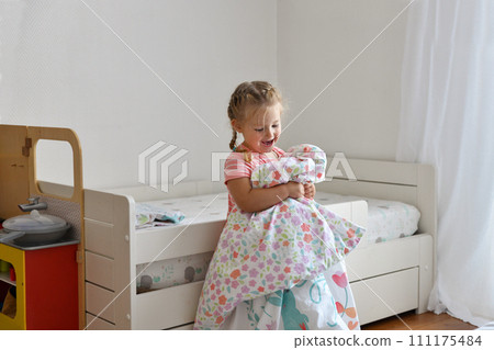 A girl makes a bed in the childrens room A girl makes a bed in the childrens room 111175484
