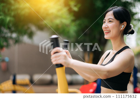 Young asian athletic sportswoman 30s wearing sportswear listening relaxing music while working out exercise equipment outdoor in park. Healthy lifestyle concept 111175632