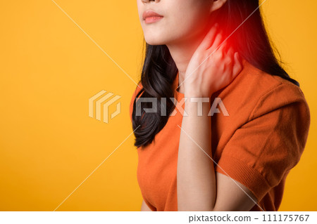 Young asian woman 30s wearing orange shirt holding her pain neck isolated on yellow background. office syndrome health care concept. Young asian woman 30s wearing orange shirt holding her pain neck isolated on yellow background. office syndrome health care concept. 111175767