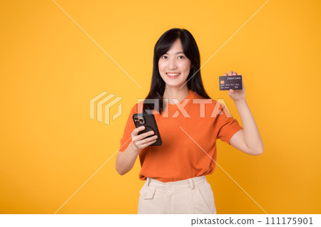 Dynamic young Asian woman in her 30s, using smartphone and holding credit card on yellow background. Secure online payment. Dynamic young Asian woman in her 30s, using smartphone and holding credit card on yellow background. Secure online payment. 111175901