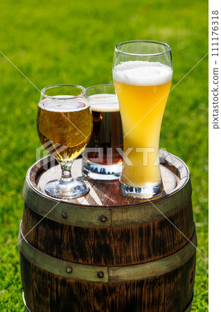 Variety of beer glasses on rustic wooden barrel 111176318