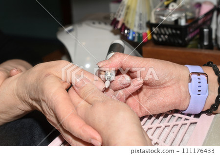 A manicurist works with a milling cutter. A manicurist works with a milling cutter. 111176433