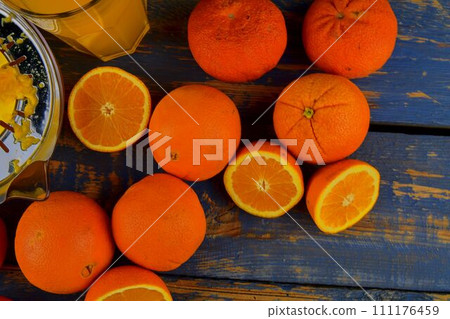 Tangerines, oranges, a glass of orange juice and manual citrus squezeer on blue wooden background. Oranges cut in half. Top view, flat design 111176459