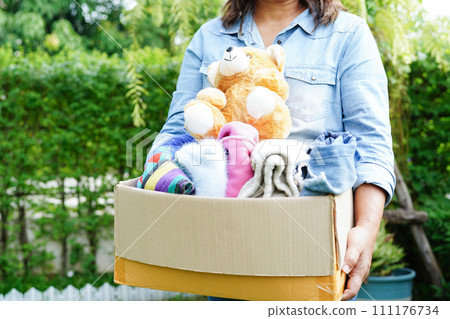 Volunteer collect cloth and doll in cardboard box to donate. 111176734