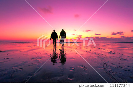 Sunset Stroll: Couple's Silhouette Against a Vibrant Sky Sunset Stroll: Couple's Silhouette Against a Vibrant Sky 111177244