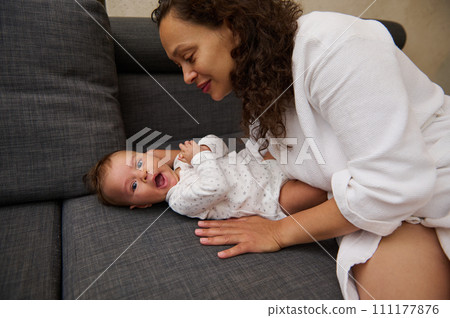 Smiling woman enjoying nice moments with her baby boy indoor. Childcare. Childbirth. Maternity leave and infancy concept 111177876