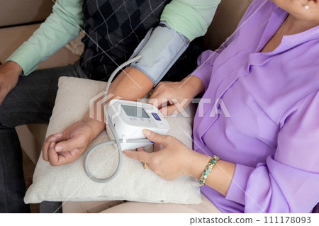 Closeup hands asian senior couple sitting on sofa checking blood pressure with pressure gauge. 111178093