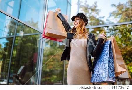 Stylish woman with shopping bags walks through the city streets. Spring Style. Stylish woman with shopping bags walks through the city streets. Spring Style. 111178697
