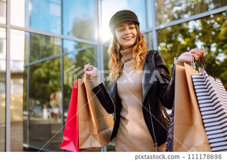 Stylish woman with shopping bags walks through the city streets. Spring Style. Stylish woman with shopping bags walks through the city streets. Spring Style. 111178698