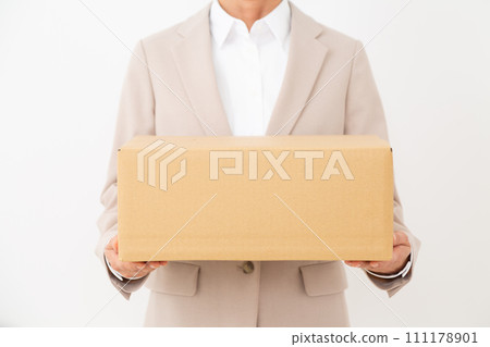 穿著西裝的中年婦女攜帶紙箱行李 穿著西裝的中年婦女攜帶紙箱行李 111178901