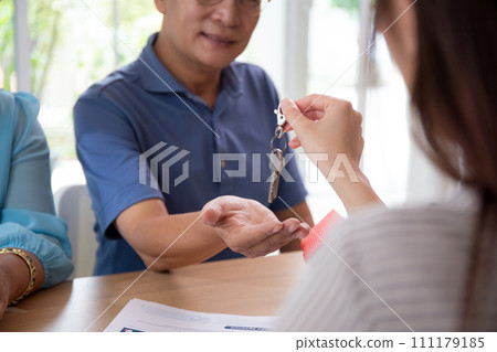 Real estate agent woman giving key form home with happiness with elderly couple. Real estate agent woman giving key form home with happiness with elderly couple. 111179185