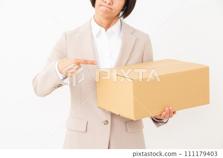 A middle-aged woman in a suit worries about carrying cardboard box luggage. A middle-aged woman in a suit worries about carrying cardboard box luggage. 111179403