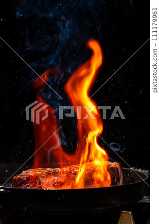 Sirloin steak being cooked surrounded by flames Sirloin steak being cooked surrounded by flames 111179961