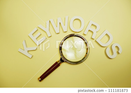 Kewords letters and magnifying top view on yellow background 111181873