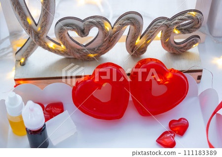 Handmade homemade soap in the shape of hearts for a Valentine's Day gift to your beloved. Perfumes and dyes, soap base on the table 111183389