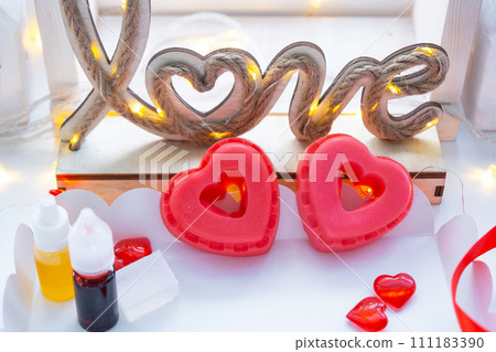 Handmade homemade soap in the shape of hearts for a Valentine's Day gift to your beloved. Perfumes and dyes, soap base on the table 111183390