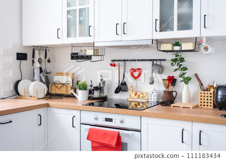 The interior of the kitchen in the house is decorated with red hearts for Valentine's Day. Decor on the table, stove, utensils, festive mood in a family nest The interior of the kitchen in the house is decorated with red hearts for Valentine's Day. Decor on the table, stove, utensils, festive mood in a family nest 111183434