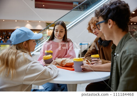 Teenage friends having snack during walk in shopping center 111184468