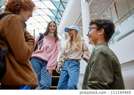 Happy teenage friends team moving staircase at shopping mall Happy teenage friends team moving staircase at shopping mall 111184469