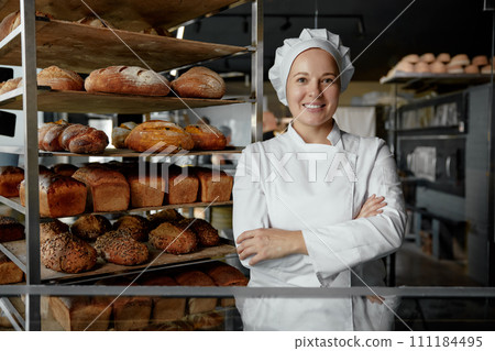 Happy woman baker chef standing near showcases 111184495