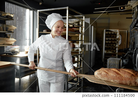 Freshly baked artisan bread on shovel in female baker hands Freshly baked artisan bread on shovel in female baker hands 111184500