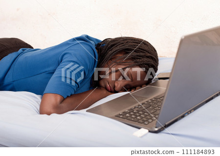 woman sleeping on the bed in front of a laptop 111184893
