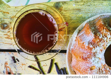 Old fashioned sand cake with cup of black tea and pieces of vanilla on wooden background. Egg-yolk sponge cake on rustic white background. Top view. Flat design Old fashioned sand cake with cup of black tea and pieces of vanilla on wooden background. Egg-yolk sponge cake on rustic white background. Top view. Flat design 111184906