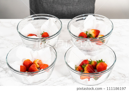 Freshly washed and dried strawberries are carefully arranged in a glass bowl lined with paper towel, ready for snacking or further use. Freshly washed and dried strawberries are carefully arranged in a glass bowl lined with paper towel, ready for snacking or further use. 111186197