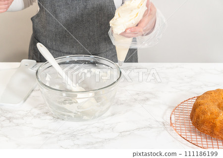 The creamy and delicious cream cheese buttercream frosting is artfully transferred to a piping bag, featuring a round metal piping tip, ready for decorating the Carrot Bundt Cake. The creamy and delicious cream cheese buttercream frosting is artfully transferred to a piping bag, featuring a round metal piping tip, ready for decorating the Carrot Bundt Cake. 111186199