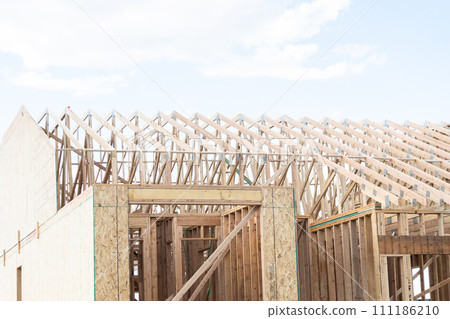 An ongoing construction site in the suburbs, featuring the framing stage of a single-family house. An ongoing construction site in the suburbs, featuring the framing stage of a single-family house. 111186210