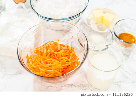 The measured ingredients are placed in mixing bowls on the counter, preparing to bake a scrumptious Carrot Bundt Cake from a cake mix. The measured ingredients are placed in mixing bowls on the counter, preparing to bake a scrumptious Carrot Bundt Cake from a cake mix. 111186226