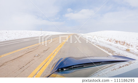 Navigating a frontage road post-winter storm offers a serene drive. The surrounding landscape, blanketed in snow, contributes to the peaceful and picturesque environment, enhancing the driving 111186295