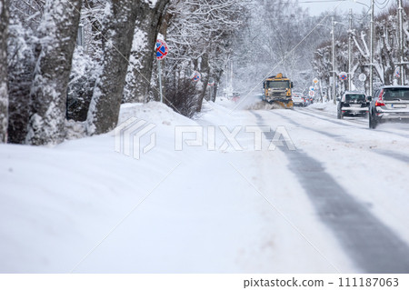 A snowplow is coming, cleaning the snow after a heavy snowfall in a harsh winter A snowplow is coming, cleaning the snow after a heavy snowfall in a harsh winter 111187063